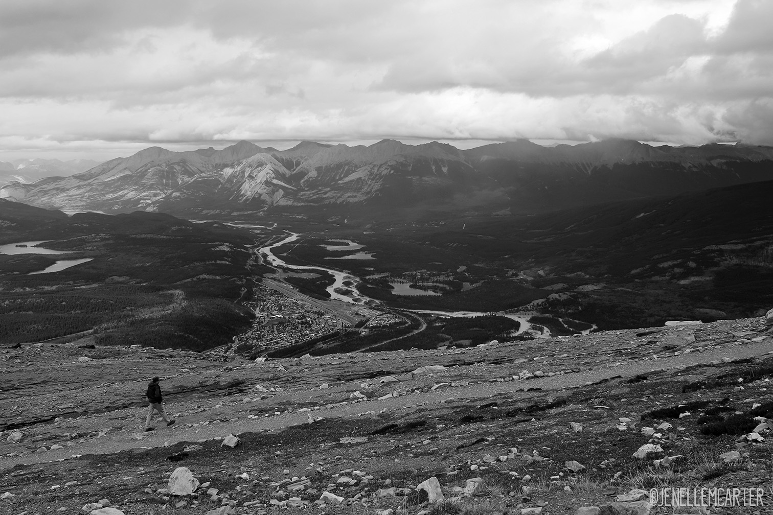 A man walks a trail on top of a mountain.